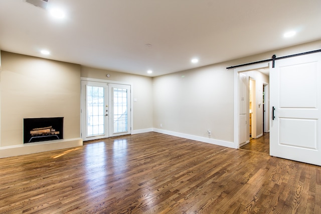 unfurnished living room featuring dark hardwood / wood-style floors, a barn door, and french doors