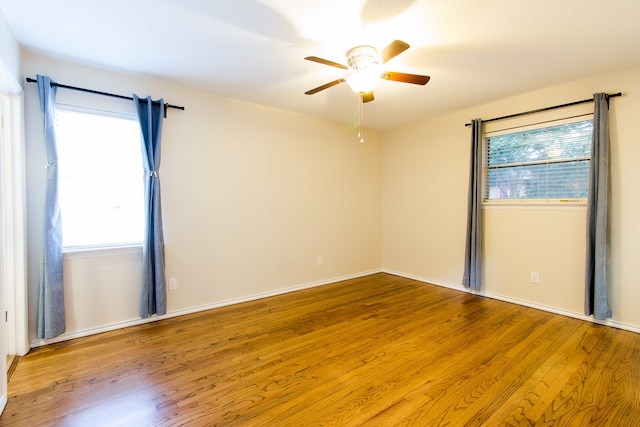 unfurnished room with ceiling fan, plenty of natural light, and wood-type flooring