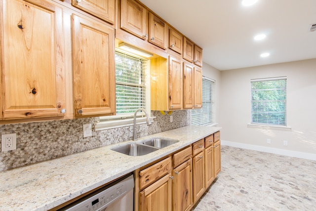 kitchen featuring backsplash, sink, plenty of natural light, and light stone counters