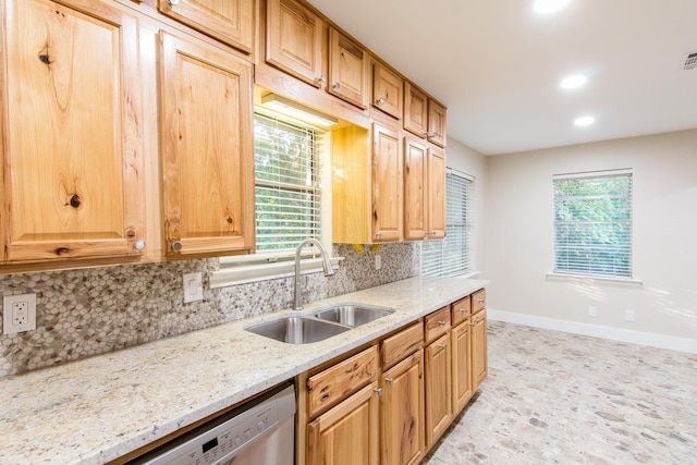 kitchen featuring light stone counters, stainless steel dishwasher, sink, and decorative backsplash