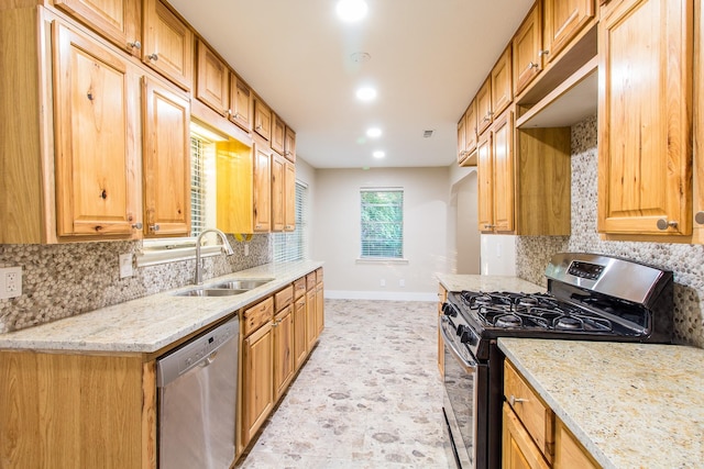 kitchen featuring stainless steel appliances, tasteful backsplash, sink, and light stone counters