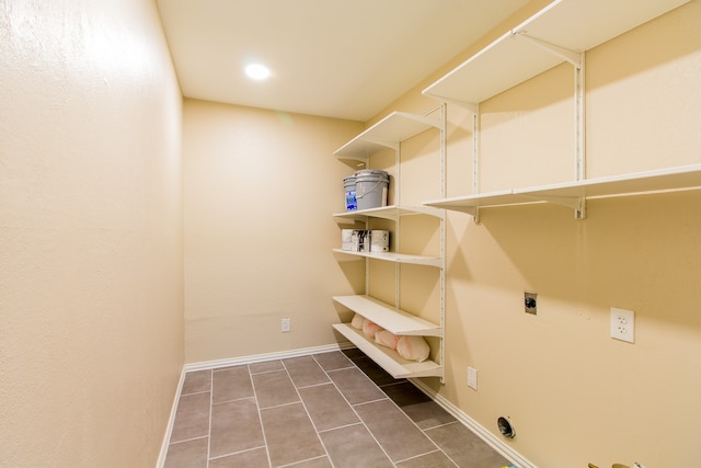 clothes washing area featuring dark tile patterned flooring and electric dryer hookup