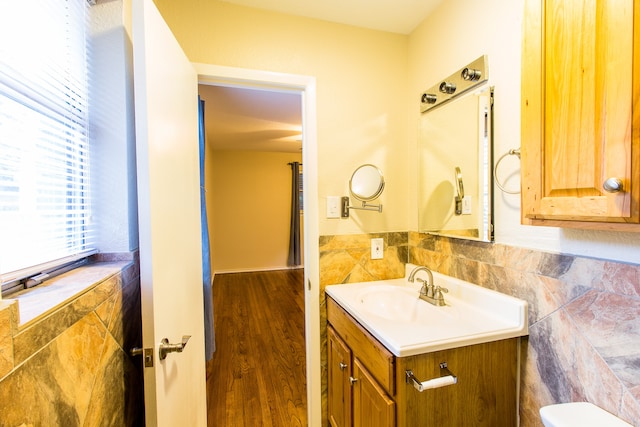 bathroom featuring tile walls, toilet, vanity, and wood-type flooring