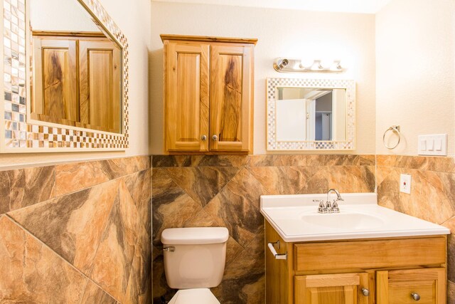 bathroom with tile walls, toilet, vanity, and tasteful backsplash