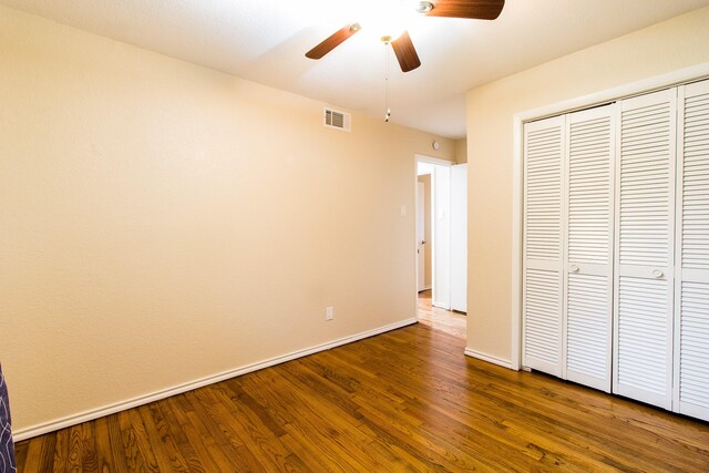 unfurnished bedroom with dark wood-type flooring, a closet, and ceiling fan