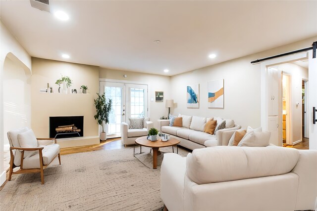 living room featuring french doors, wood-type flooring, and a barn door