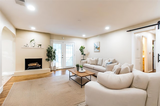 living room featuring french doors, a barn door, and light wood-type flooring