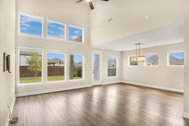 unfurnished living room with plenty of natural light, a towering ceiling, and dark hardwood / wood-style flooring