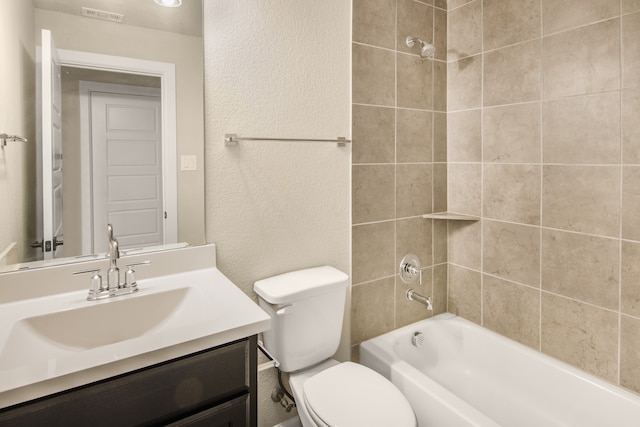 full bathroom with tiled shower / bath, vanity, and toilet