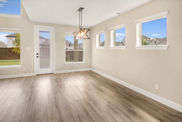 unfurnished dining area with light hardwood / wood-style floors, a chandelier, and a wealth of natural light