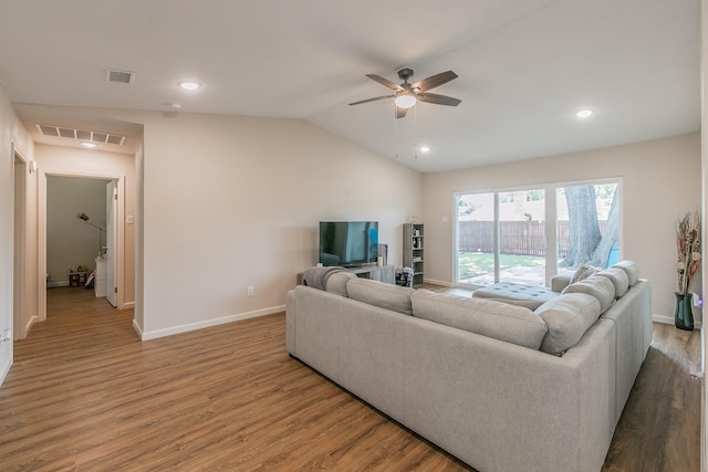 living room featuring lofted ceiling, visible vents, baseboards, and wood finished floors