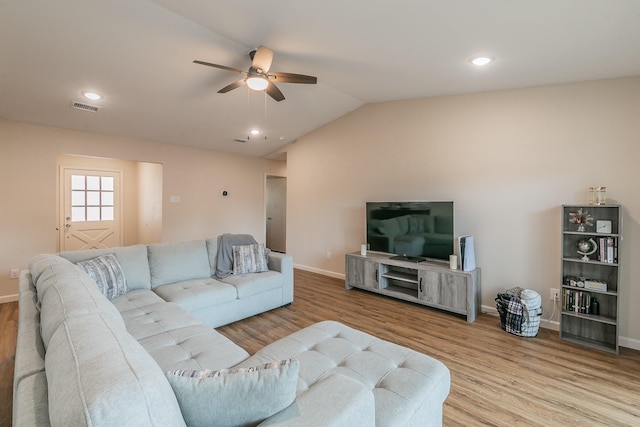 living room featuring light wood-type flooring, visible vents, vaulted ceiling, and baseboards