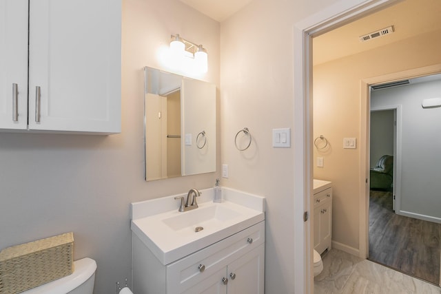 bathroom with toilet, marble finish floor, vanity, and visible vents