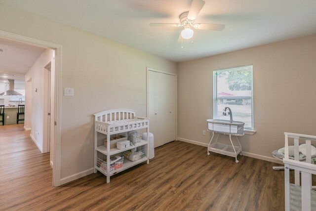 bedroom featuring dark wood-style floors, a closet, ceiling fan, and baseboards