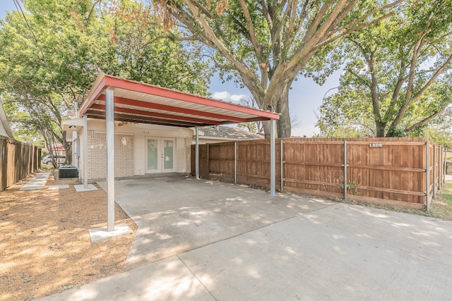 view of parking featuring driveway, french doors, and fence