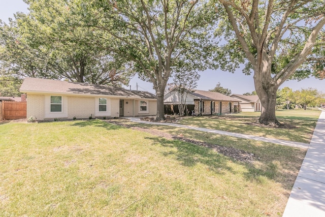 ranch-style home featuring a front yard, brick siding, and fence