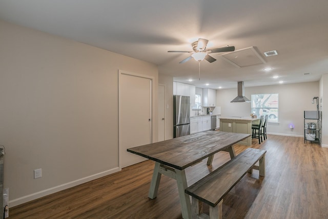 dining space featuring wood finished floors, a ceiling fan, visible vents, baseboards, and attic access