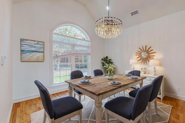 dining area featuring lofted ceiling, a notable chandelier, plenty of natural light, and light hardwood / wood-style floors