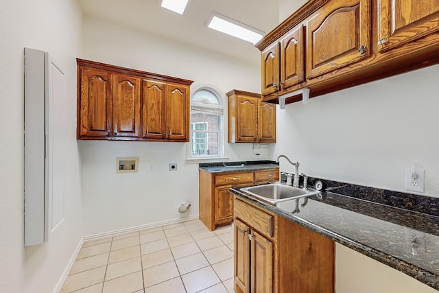 kitchen with light tile patterned flooring, dark stone countertops, and sink