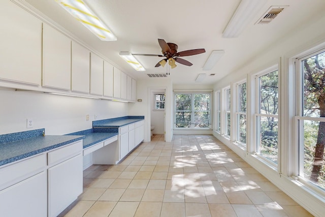 interior space with light tile patterned flooring, ceiling fan, a wealth of natural light, and white cabinetry