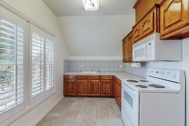 kitchen with white appliances, backsplash, vaulted ceiling, and plenty of natural light