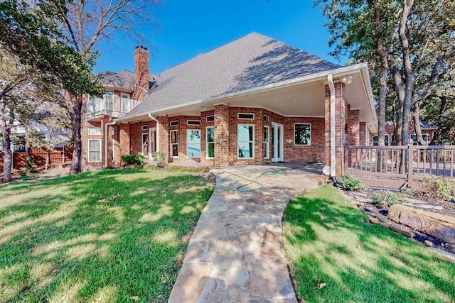 rear view of property with a yard, a balcony, and a patio area