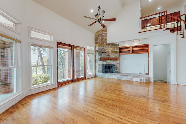 unfurnished living room with a fireplace, high vaulted ceiling, light hardwood / wood-style flooring, and ceiling fan