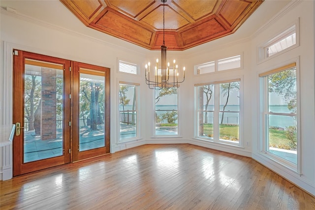 unfurnished dining area featuring light wood-type flooring, crown molding, and an inviting chandelier