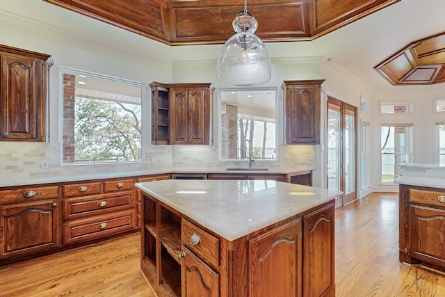 kitchen featuring decorative backsplash, ornamental molding, a kitchen island, and light hardwood / wood-style flooring