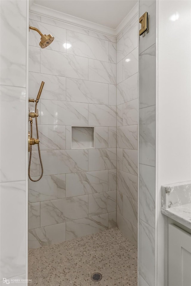 bathroom with a tile shower and ornamental molding