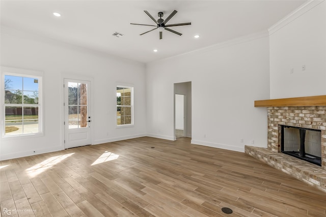 unfurnished living room with ceiling fan, light wood-type flooring, ornamental molding, and a fireplace