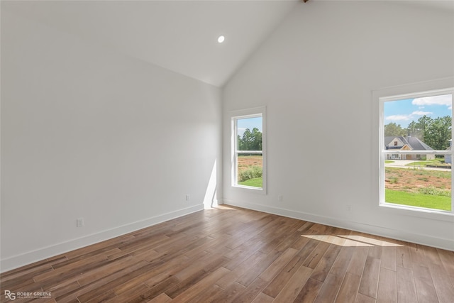 unfurnished room with hardwood / wood-style flooring, a wealth of natural light, and high vaulted ceiling