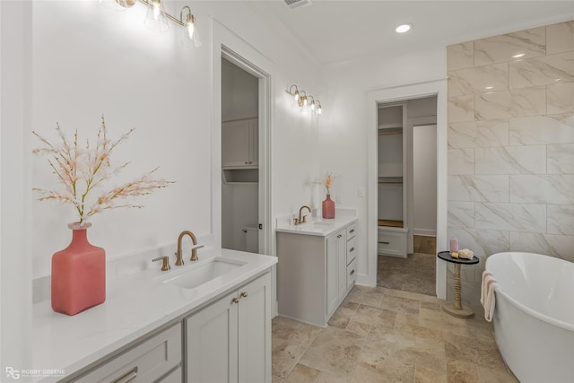 bathroom with vanity, crown molding, a tub, and tile walls