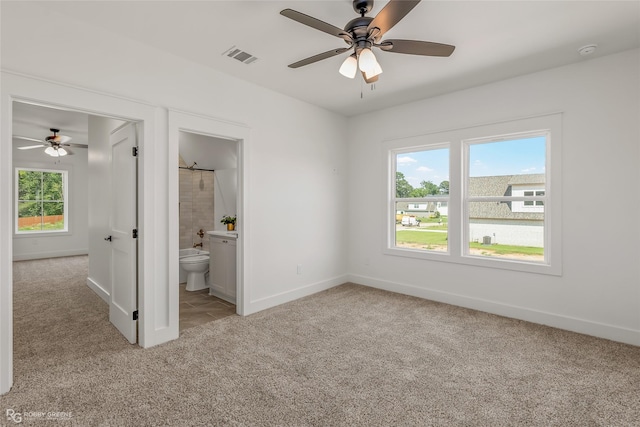 unfurnished bedroom featuring ceiling fan, light colored carpet, and ensuite bathroom