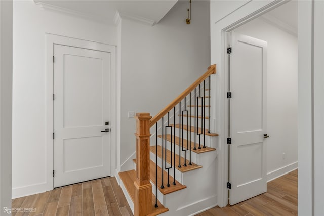 staircase featuring hardwood / wood-style floors and crown molding