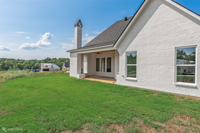 rear view of property with ceiling fan, a patio, and a lawn