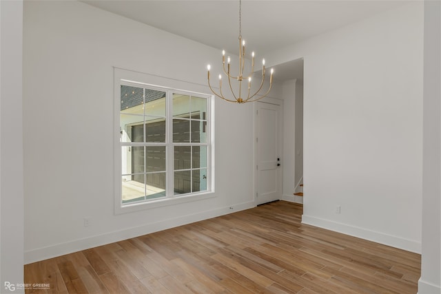 unfurnished room with light wood-type flooring and a notable chandelier