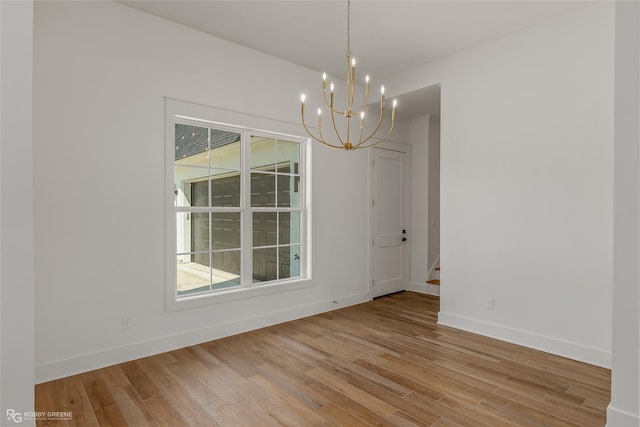 unfurnished dining area featuring a chandelier and light wood-type flooring