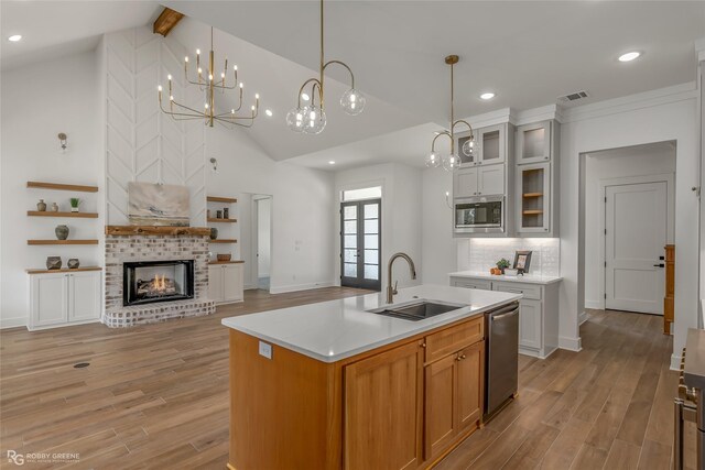 kitchen featuring decorative light fixtures, an island with sink, stainless steel appliances, and sink