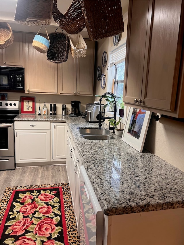 kitchen with light stone countertops, sink, light wood-type flooring, white cabinetry, and stainless steel appliances