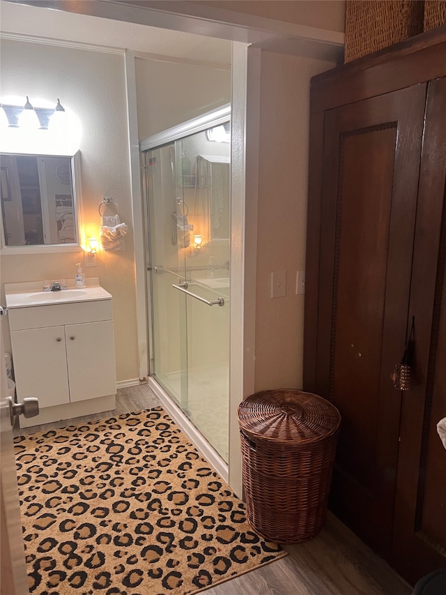 bathroom featuring a shower with door, vanity, and wood-type flooring