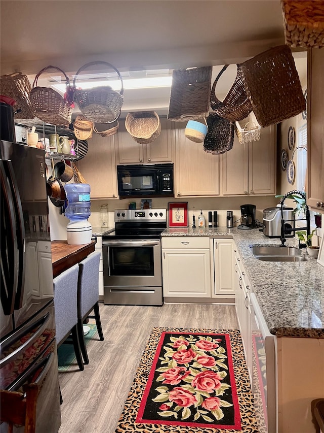 kitchen with stainless steel electric range oven, refrigerator with ice dispenser, sink, light hardwood / wood-style floors, and light stone counters