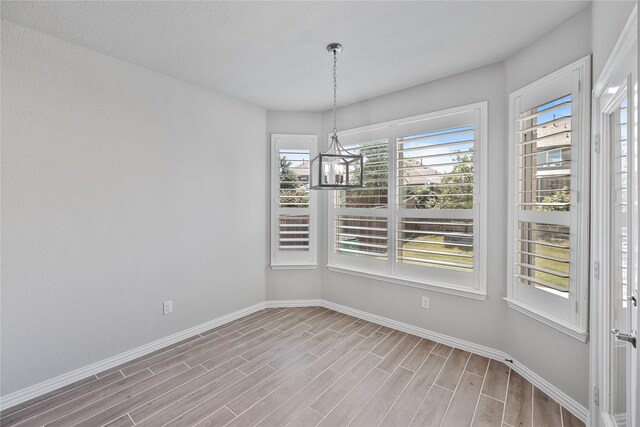 unfurnished dining area featuring plenty of natural light, a chandelier, and light hardwood / wood-style flooring