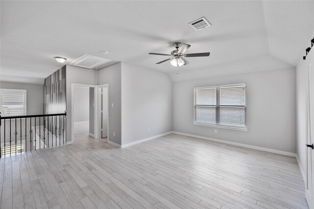 spare room with a wealth of natural light, ceiling fan, and light hardwood / wood-style floors