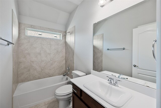 full bathroom with vanity, tile patterned floors, tiled shower / bath, vaulted ceiling, and toilet