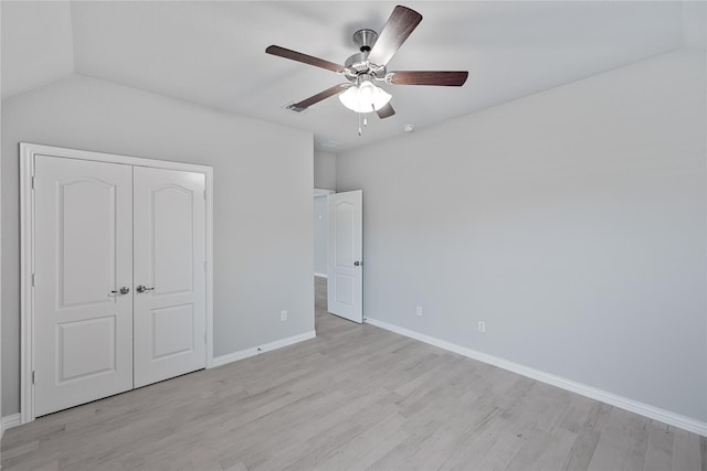 unfurnished bedroom featuring light wood-type flooring, a closet, vaulted ceiling, and ceiling fan