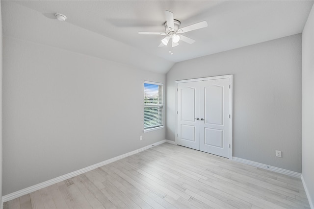 unfurnished bedroom featuring ceiling fan, a closet, light hardwood / wood-style floors, and vaulted ceiling