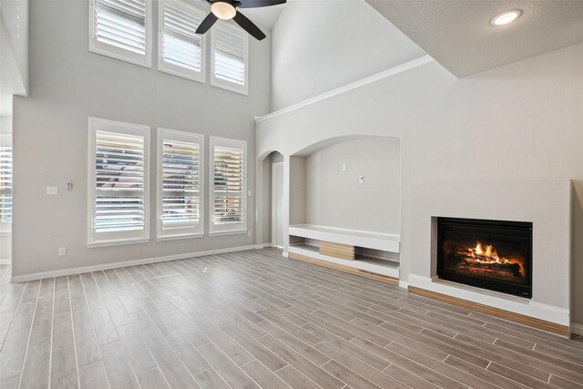 unfurnished living room featuring ceiling fan, a high ceiling, and hardwood / wood-style flooring