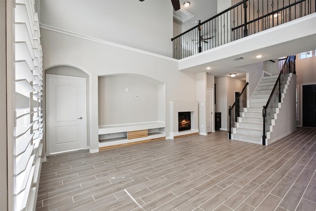 unfurnished living room with a towering ceiling and ornamental molding