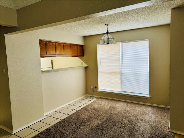 unfurnished dining area with light colored carpet and a textured ceiling